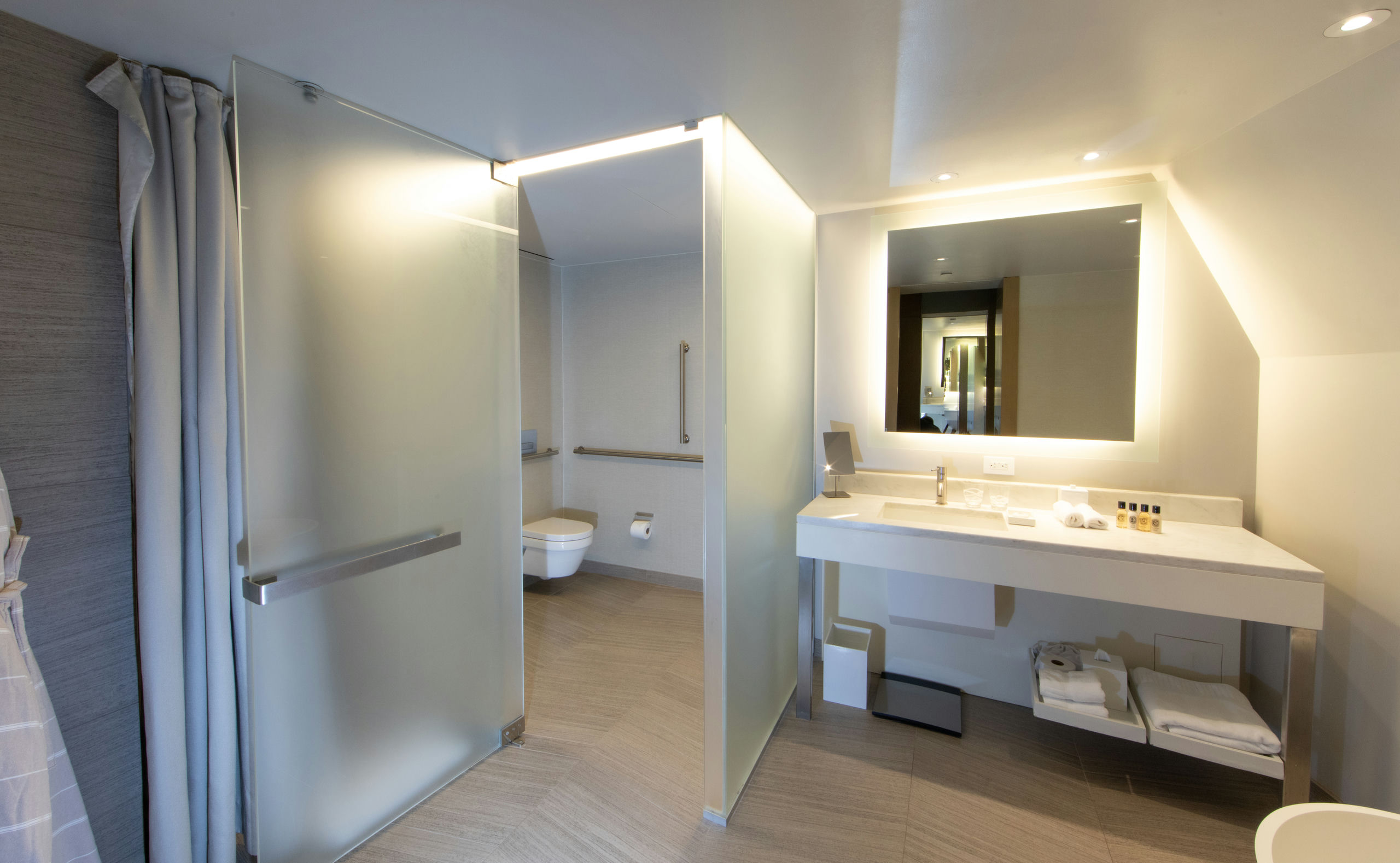 A modern bathroom with a double vanity, shower, toilet, and mirror.