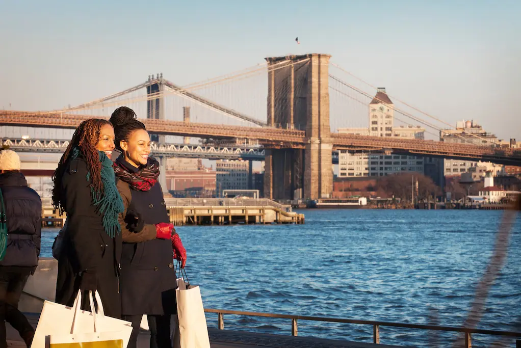 people getting their photo taken with the brooklyn bridge behind them