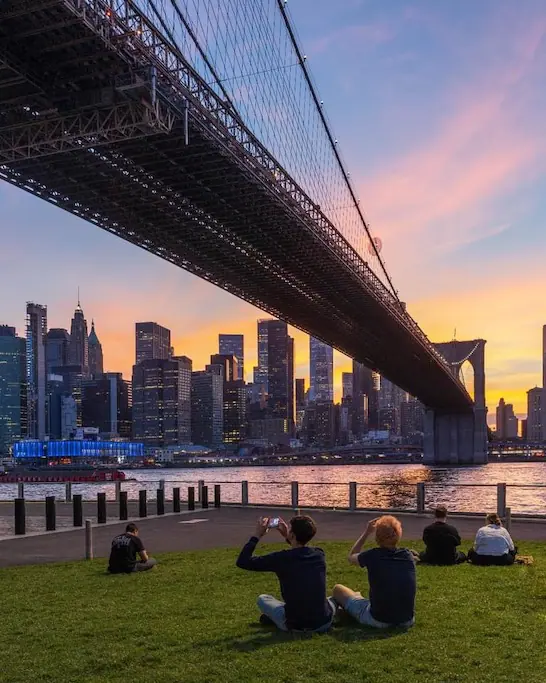 people sitting under the brooklyn bridge