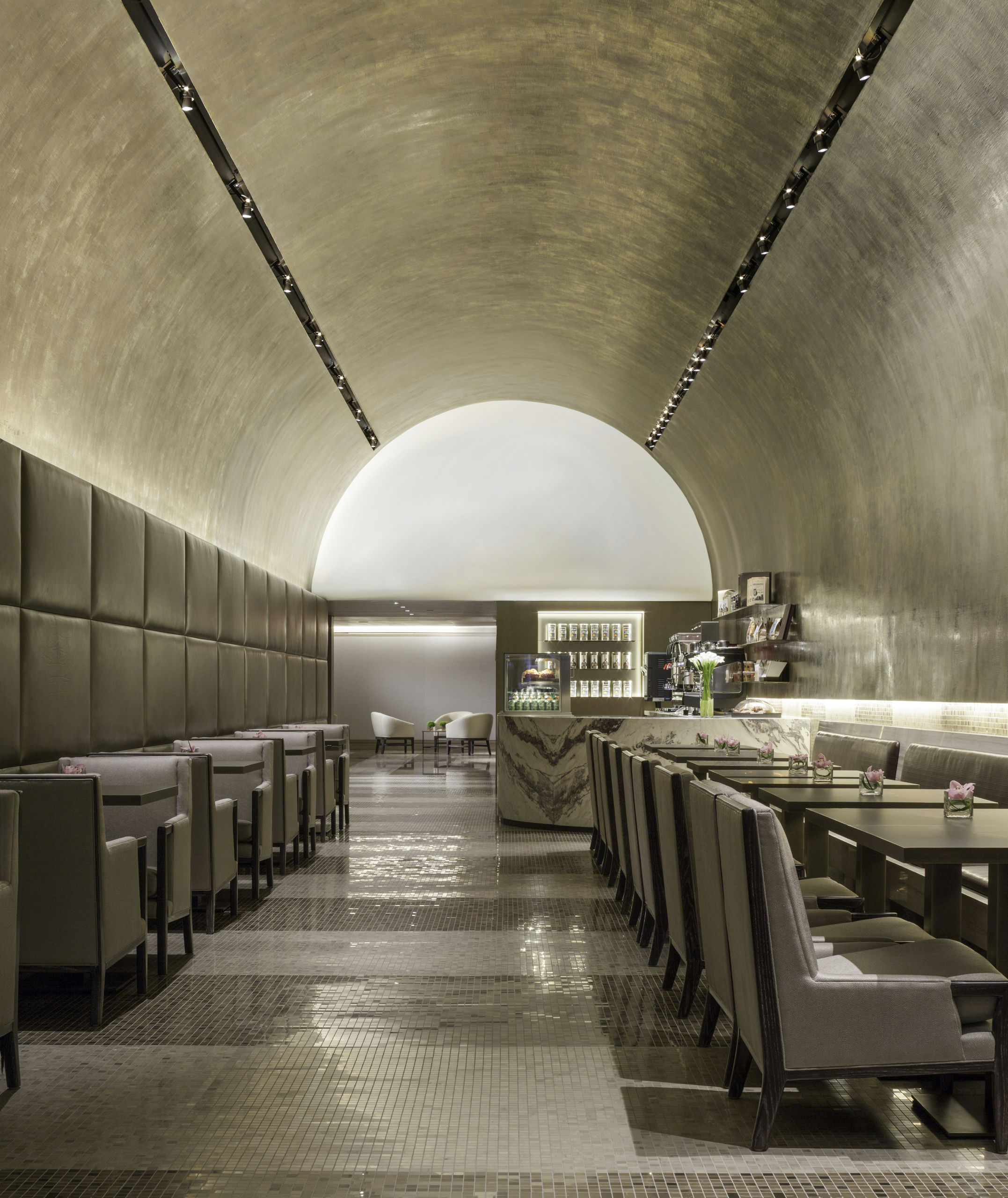 A long, curved dining area with tables and booth seating under an arched ceiling.