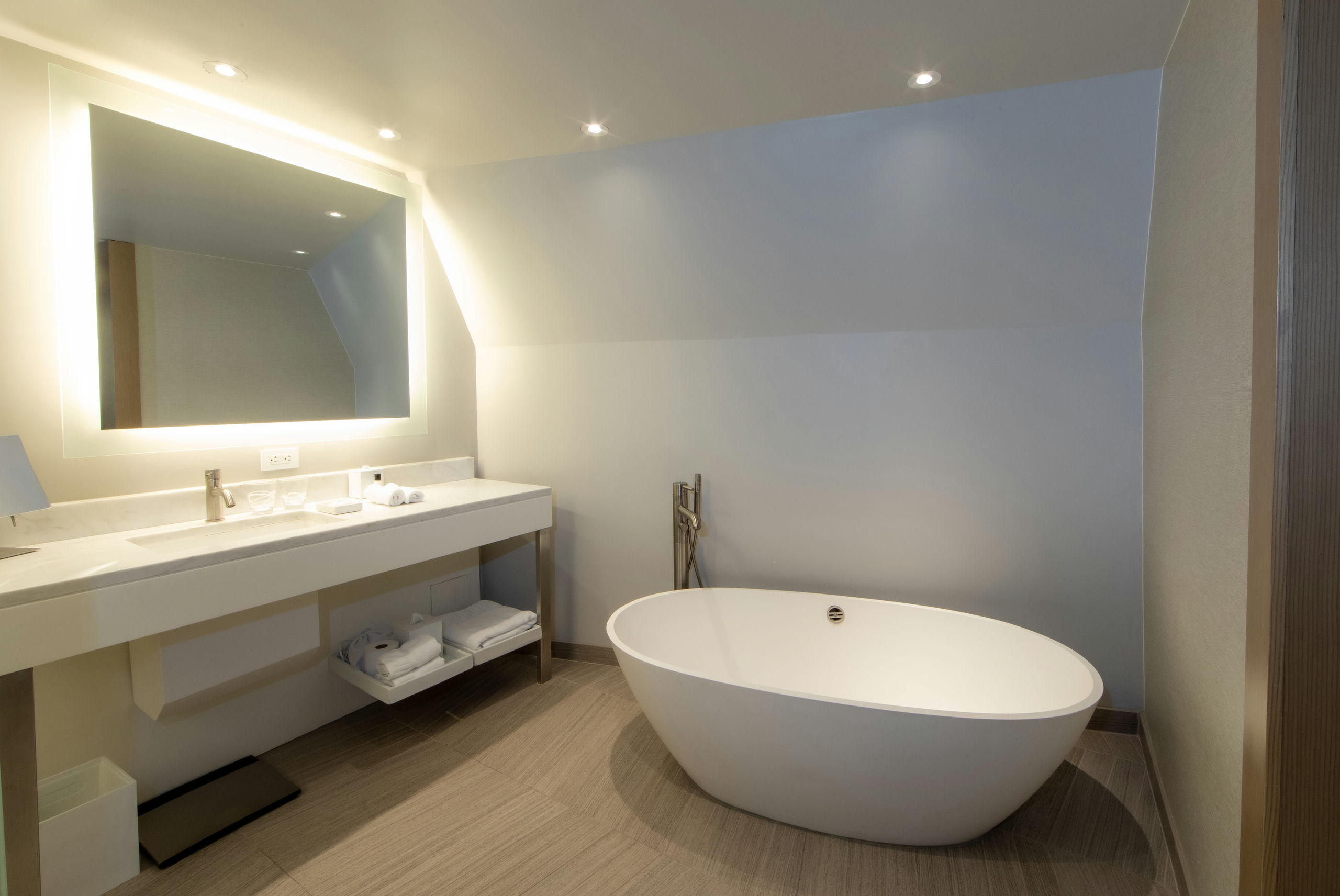 A modern bathroom with a freestanding tub, double sink, and large mirror