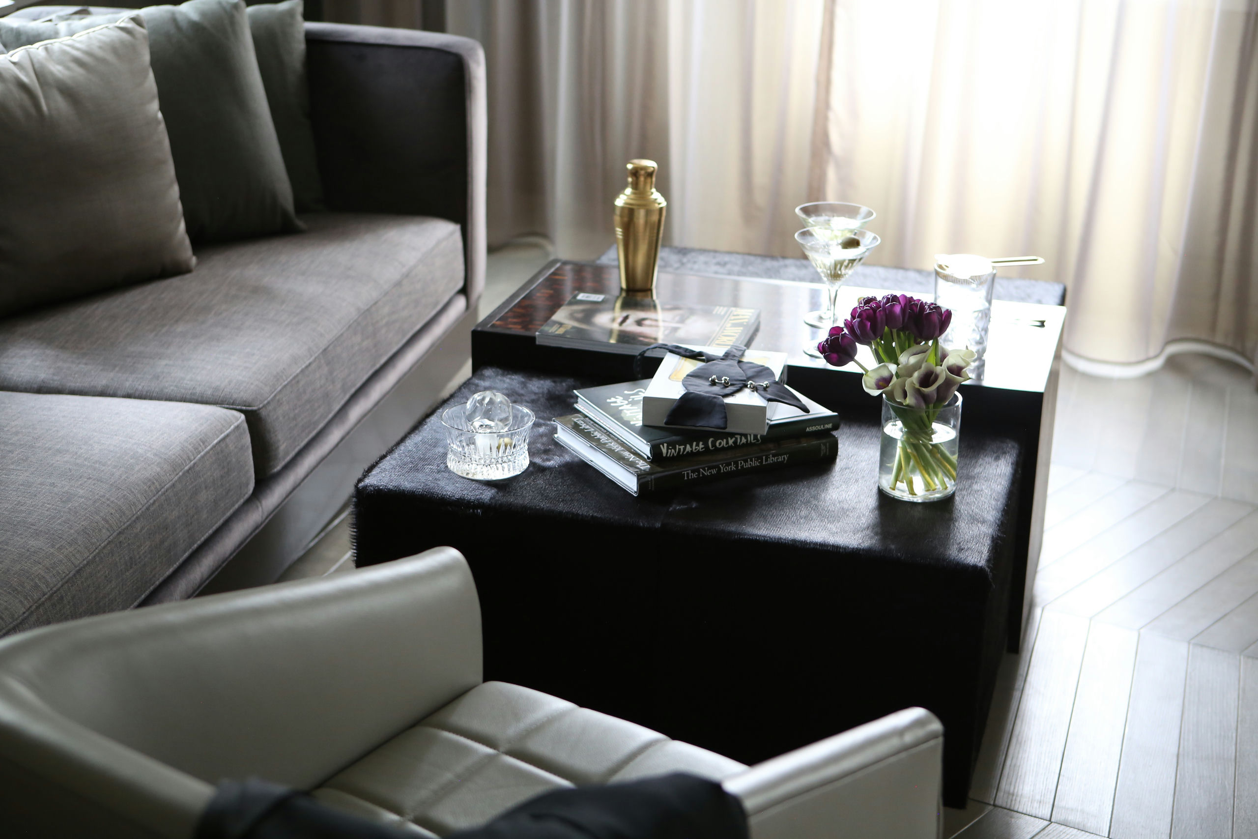 A stylish living room with a gray sofa, a black coffee table, and a white leather chair.