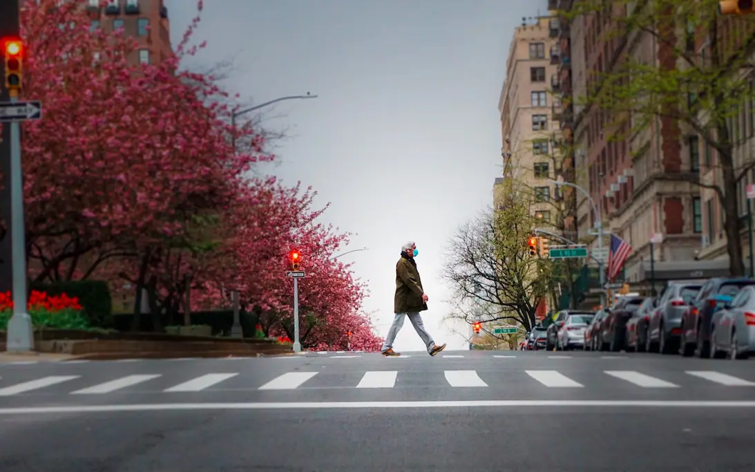 man wearing a mask walking across the street