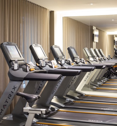 A row of Matrix brand treadmills in a gym with a mirror on the wall