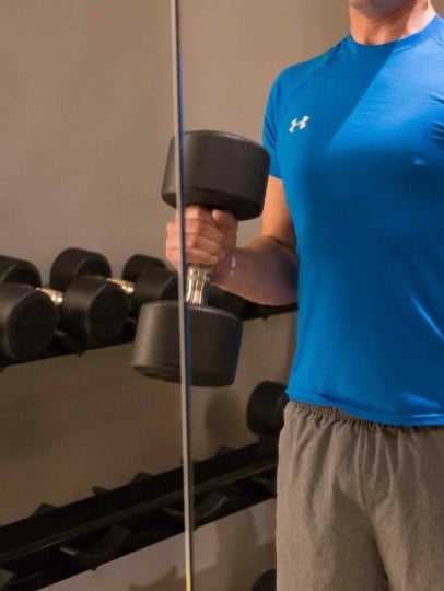A man lifting dumbbells in a gym.