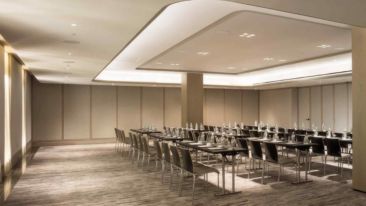 A large, empty meeting room with long tables and chairs arranged in rows.