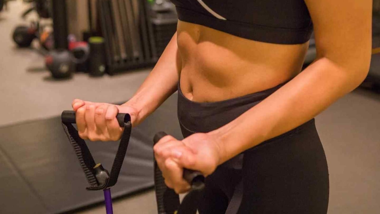 A woman in black workout attire exercising with resistance bands in a gym.