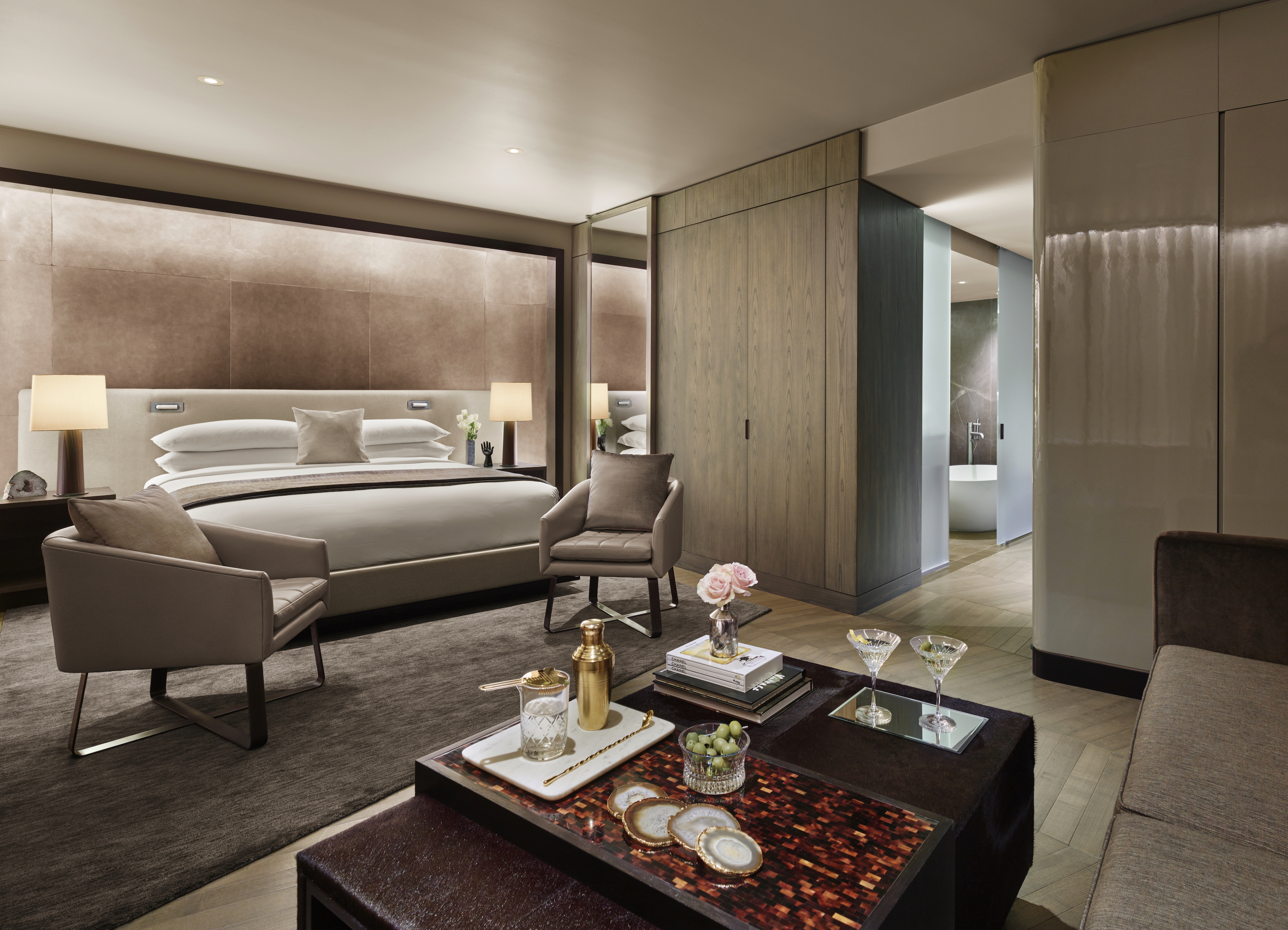 A luxurious hotel room with a large bed, seating area, and modern decor.